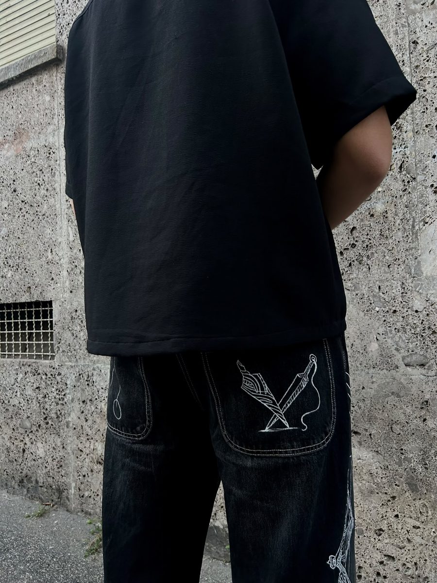 Retro dei jeans neri indossati, con lame incrociate sulla tasca