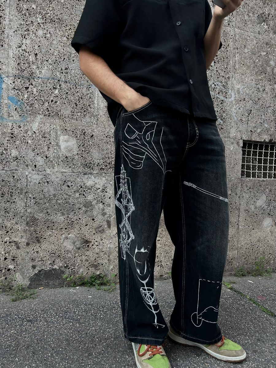 Jeans neri a gamba larga indossati, mano in tasca